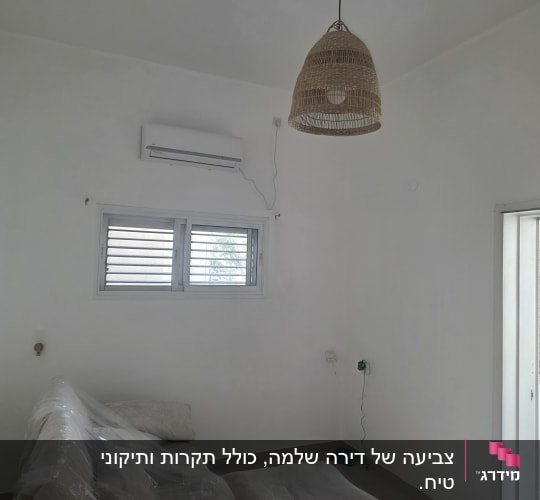 סלון עם ספה מכוסה בניילון ומזגן על הקיר